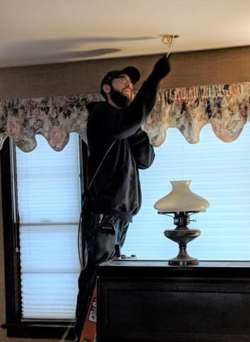 photo of Decker Electric technician installing ceiling lighting inside a home