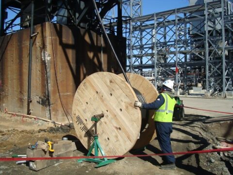 Image of a large coil of piping being handled by a Decker Electric technician at a downstream facility