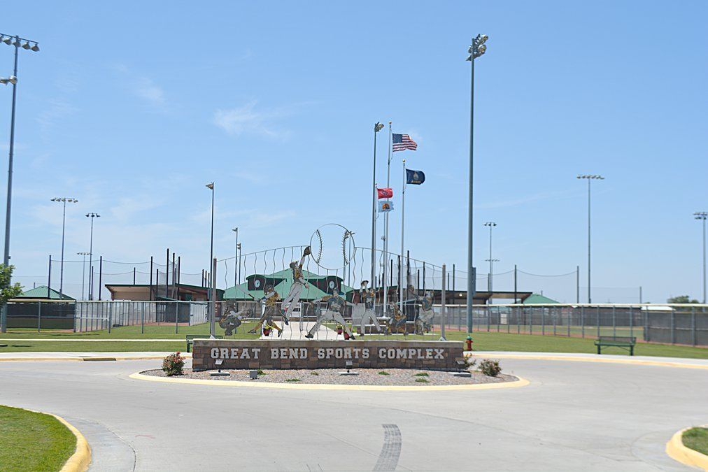 Image of the sign outside area of the Great Bend Sports Complex including flags and field lighting